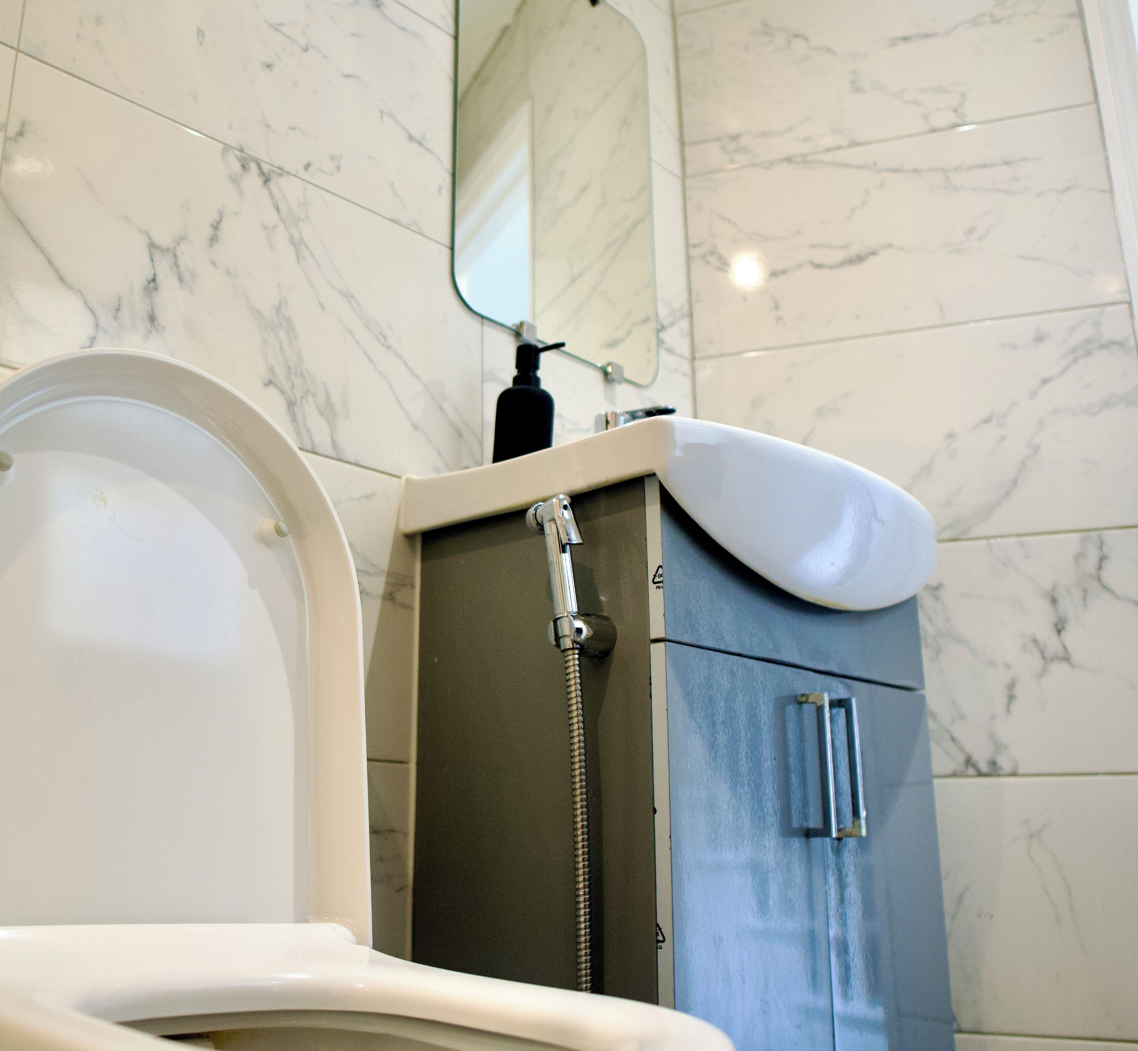 A bathroom with a toilet, a shower, and a cabinet.