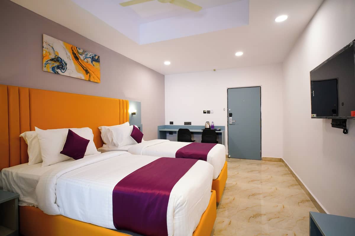 A hotel room with two beds, a desk, and a TV.