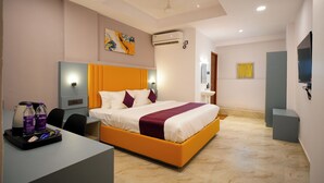 Ein modernes Hotelzimmer mit einem großen Bett, einem Schreibtisch mit Kaffeemaschine und einem Fernseher.
