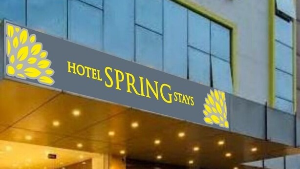 Ein Hotel Eingang mit einem Schild mit der Aufschrift 'HOTEL SPRING STAYS', einer Treppe und Blumentöpfen.