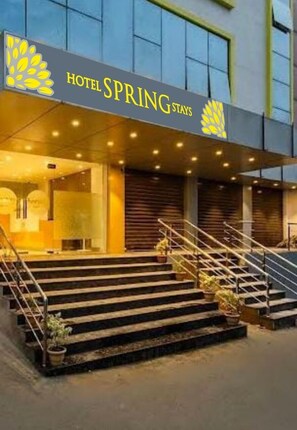 Hotellin sisäänkäynti, jossa on kyltti, jossa lukee ”HOTEL SPRING STAYS”, portaikko ja ruukkukasveja.