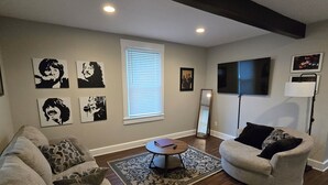Un salon comprenant un canapé, un fauteuil, une table basse et des œuvres d’art accrochées aux murs.