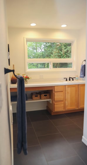 A kitchen with wooden cabinets, a white countertop, a window with a view of trees, and a hanging towel. - Sauna, River Views, 4BR Homestead Retreat (Stevenson)
