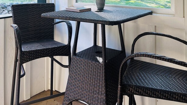 A room with a wicker table and chairs, a hanging plant, and a window with a view of greenery. - Sauna, River Views, Book Nook, 4BR Homestead Retreat (Stevenson)