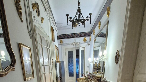 A hallway with a patterned rug, a chandelier, and ornate mirrors. - Imre Guest House (Budapest)