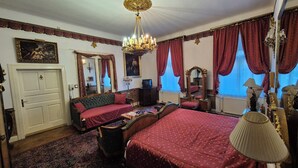 A traditional room with a bed, a sofa, a desk, and a chandelier. - Imre Guest House (Budapest)