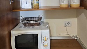 A compact kitchen with a microwave, a small refrigerator, and storage shelves. - Welcoming and well-kept, it is the perfect base for discovering the wonders of Salento. (Lizzanello)