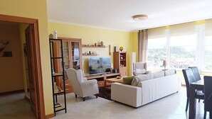 A living room with a sofa, TV, and shelves. - Casa Santa Marta Cies - Your perfect refuge with views of the Islas Cíes (Cangas)