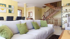A living room with a sofa, chairs, a staircase, and a bookshelf. - Casa Santa Marta Cies - Your perfect refuge with views of the Islas Cíes (Cangas)