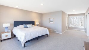A bedroom with a large bed, bedside tables, a window, and a framed picture on the wall.