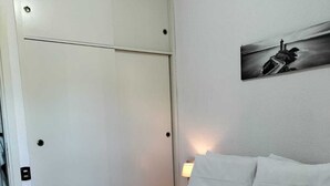 A hotel room with a bed, a nightstand, a wall-mounted painting, and a door with a handle.