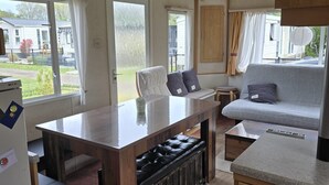 A compact kitchen with a wooden table, bench seating, and a grey sofa.