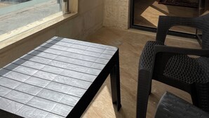 Ein Balkon mit Glastrennwand, einem Tisch und zwei Stühlen.