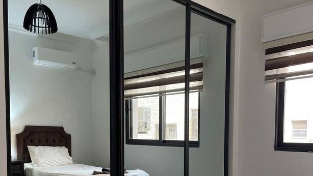 Ein Schlafzimmer mit Bett, Spiegel, Fenster und Deckenventilator.