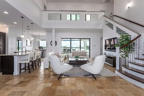 A spacious living area with a kitchen, dining space, and a staircase leading to an upper level.