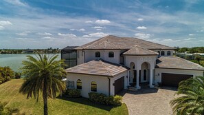 A large, multi-story house with a symmetrical design, featuring a central courtyard, a garage, and a pool.