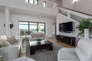 A spacious living room with a large television, a sofa set, and a coffee table.