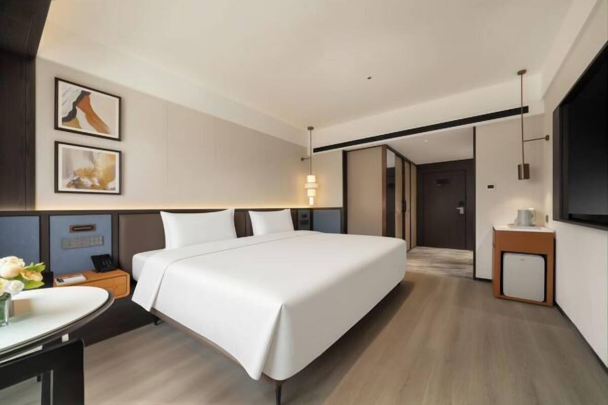 Una camera d'albergo moderna con un letto grande, comodini, una scrivania e una TV a schermo piatto.
