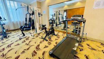 A hotel gym with exercise equipment, a treadmill, and a patterned carpet.