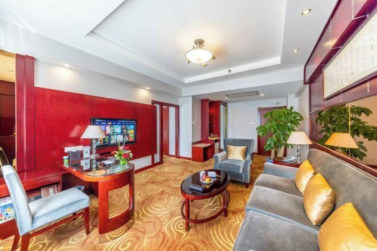 Una hall d'albergo con una parete rossa a contrasto, una reception, un divano, un tavolino da caffè e una pianta di grandi dimensioni.