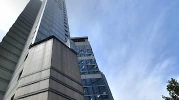 A tall building with a modern architectural design, featuring a prominent vertical element and a glass facade.