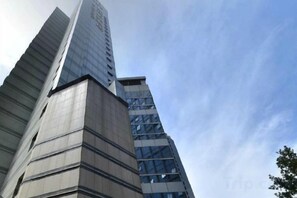 Un immeuble de grande hauteur doté d’une architecture moderne, caractérisé par un élément vertical marquant et une façade en verre.