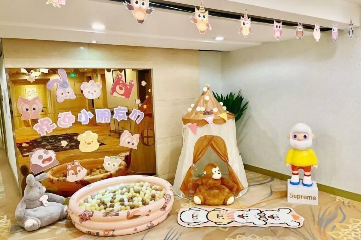 Un'area giochi per bambini con una tenda, peluche e un cartello con su scritto 'Supreme'.