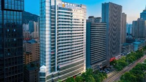 Um edifício alto com fachada de vidro moderna, cercado por outros edifícios imponentes em um horizonte urbano.
