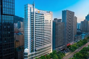 A high-rise building with a modern glass facade, surrounded by other tall buildings in a cityscape. - JJ Sun Hotel (Lanzhou)