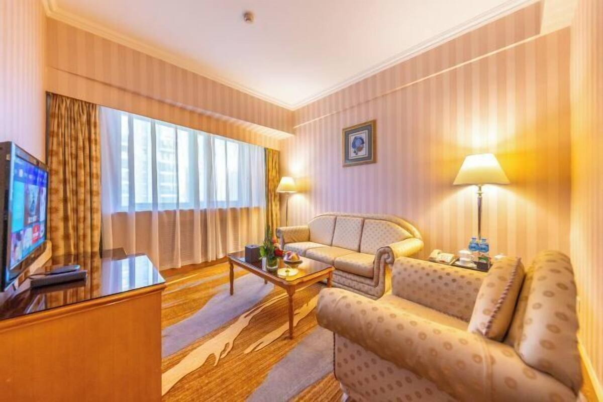 Una camera d'albergo con un divano, un tavolino, una televisione e una lampada.
