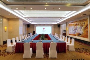 A conference room with a long table, white chairs, and a projector screen. - JJ Sun Hotel (Lanzhou)