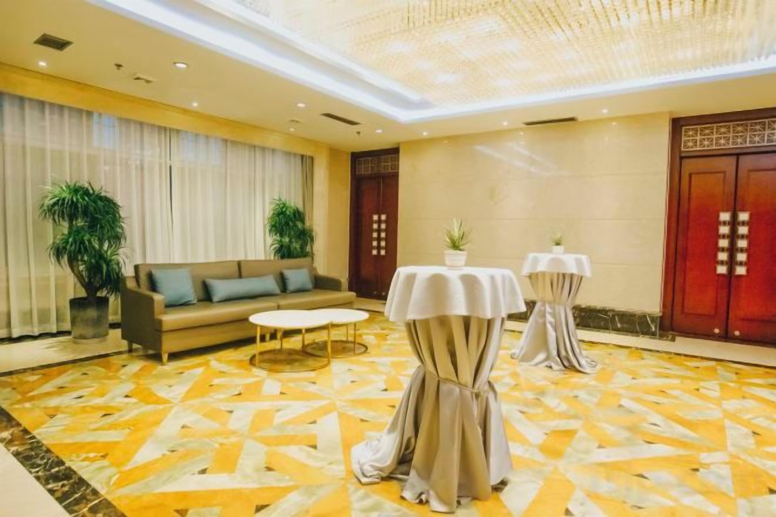 A hotel lobby with a sofa, two tables, and a patterned carpet.