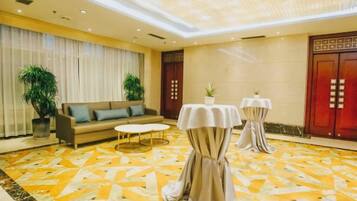A hotel lobby with a sofa, two tables, and a patterned carpet.