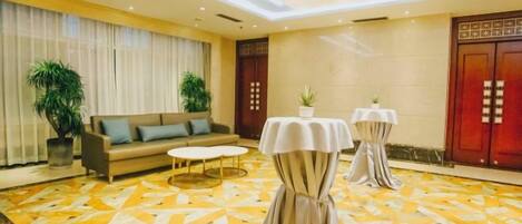 A hotel lobby with a sofa, two tables, and a patterned carpet.