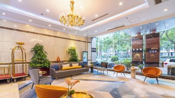 Um hall moderno com um candelabro, área de estar e janelas amplas com vista para o exterior.