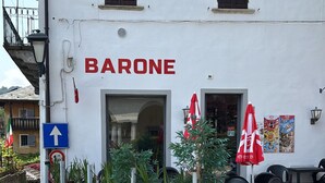 Un edificio con un letrero que dice "BARONE" y terraza al aire libre con sombrillas.