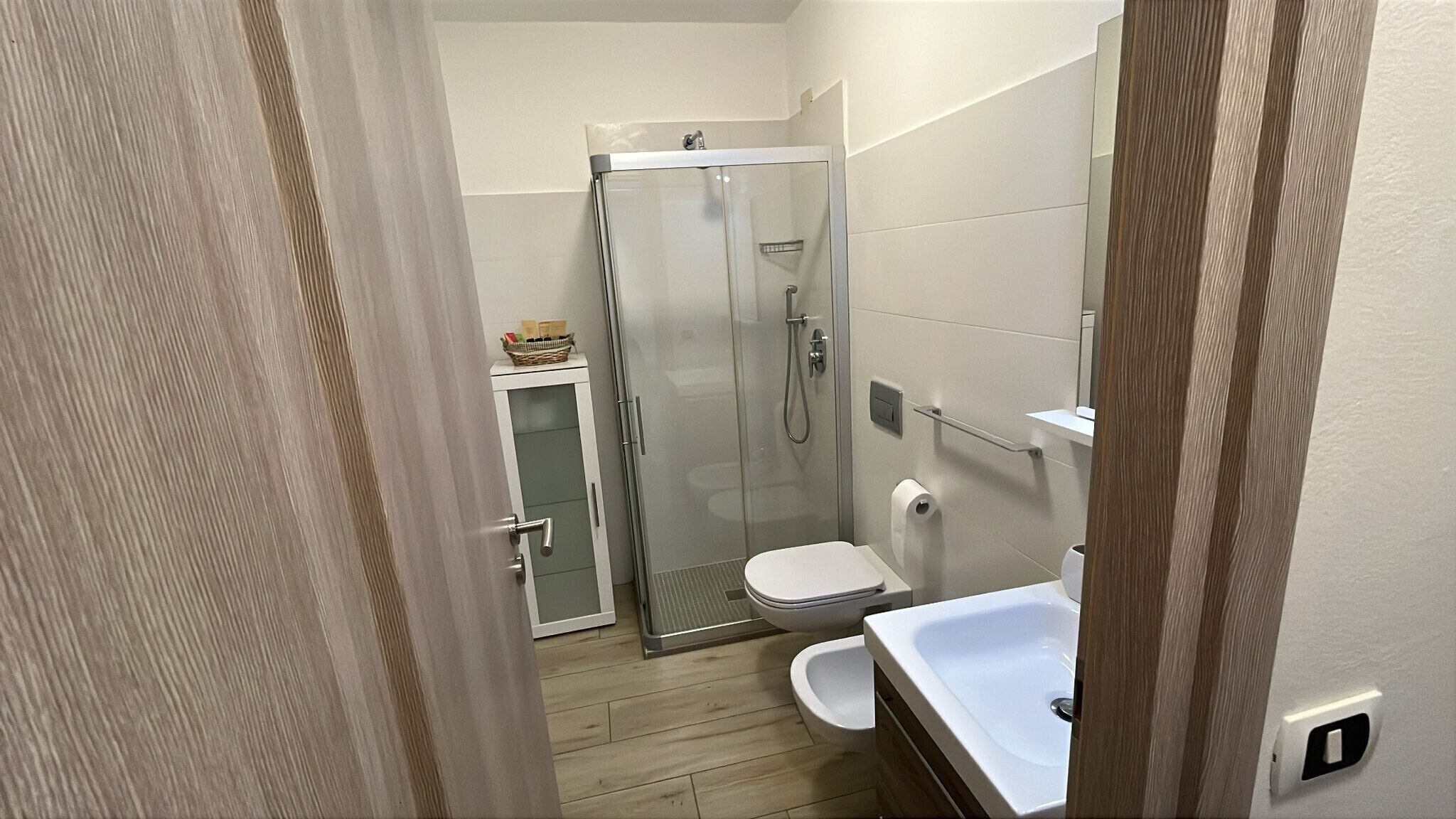 Un baño compacto con cabina de ducha de vidrio, inodoro y lavabo.
