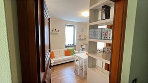 Una sala de estar acogedora con un sofá blanco, una mesa de comedor y una estantería llena de libros.