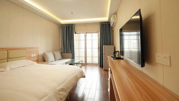 A hotel room with a bed, a desk, a TV, and a window with curtains. - Jinlu Business Hotel (Shanghai)