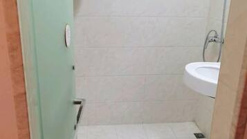 A small bathroom with a toilet, sink, and shower.