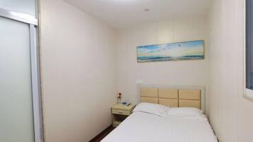 A bedroom with a bed, a nightstand, a painting, and a window.