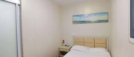 A bedroom with a bed, a nightstand, a painting, and a window.