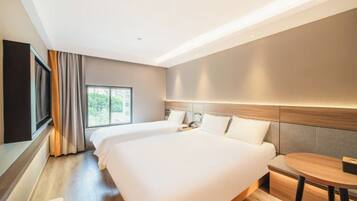 A modern hotel room with two beds, a small round table, and a large window offering a view of greenery.
