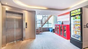 Un ascenseur moderne, un escalier et des distributeurs automatiques dans le hall d’un hôtel.
