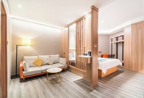 A modern hotel room with a sofa, a round coffee table, a bed, and a desk with a chair. - YanxI Hotel (Shanghai)