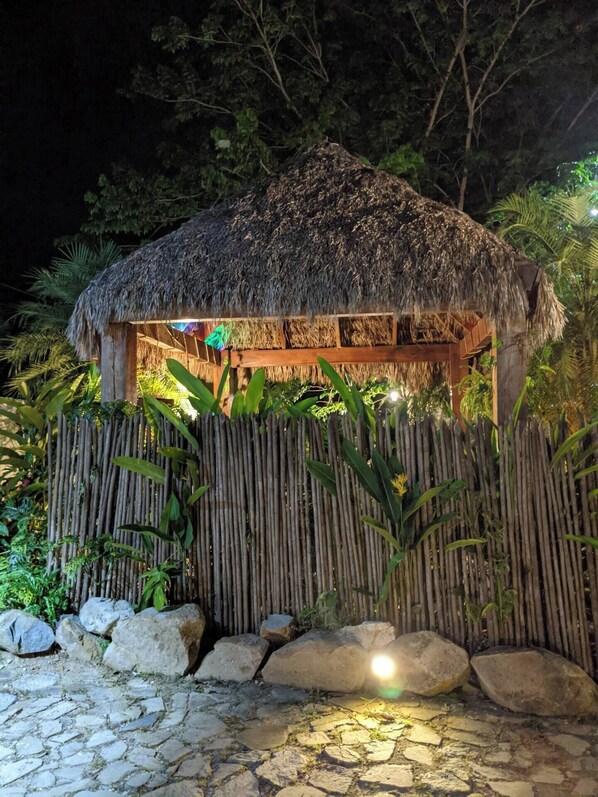 A thatched-roof hut with a bamboo fence and stone pathway.