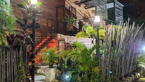 Un edificio moderno con fachada de madera, escalones de piedra que llevan a la entrada y una cerca de bambú.
