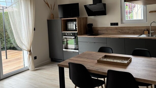 Une cuisine moderne avec une table à manger en bois, des chaises noires et un four encastré.