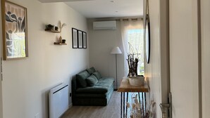 Un salon moderne avec un canapé vert, un luminaire suspendu en fibres tressées et un plancher en bois.