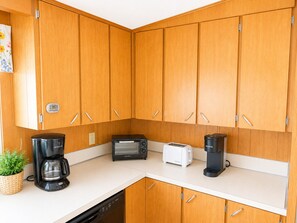 Uma cozinha compacta com armários de madeira, cafeteira, torradeira e máquina de café Keurig.
